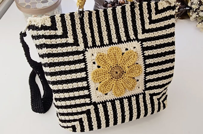 Crochet Daisy Bag Featured - The charm of a crochet daisy bag lies in its harmonious blend of artistry and practicality. With its vibrant floral centerpiece and structured yet soft body, this accessory effortlessly elevates any outfit.